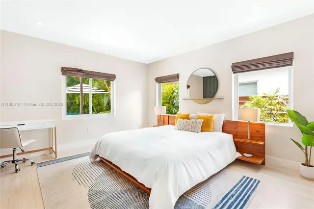 a bedroom with a bed mirror table and window