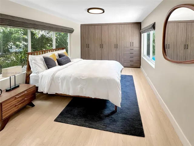 a spacious bedroom with a bed a mirror and a large window