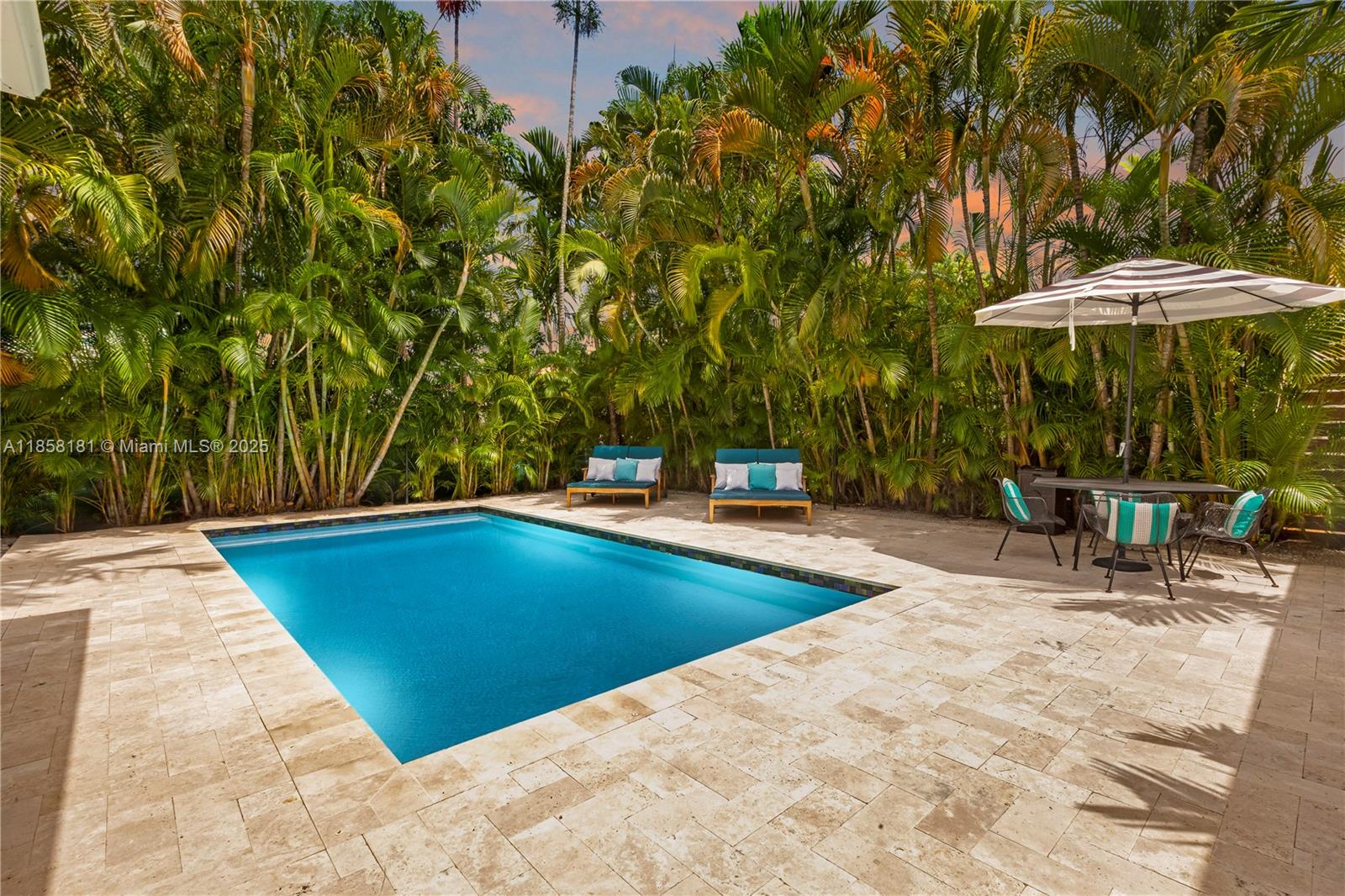 9065 Emerson Avenue Surfside, FL 33154 - Photo 45 of 50 a view of pool with a table and chairs under an umbrella