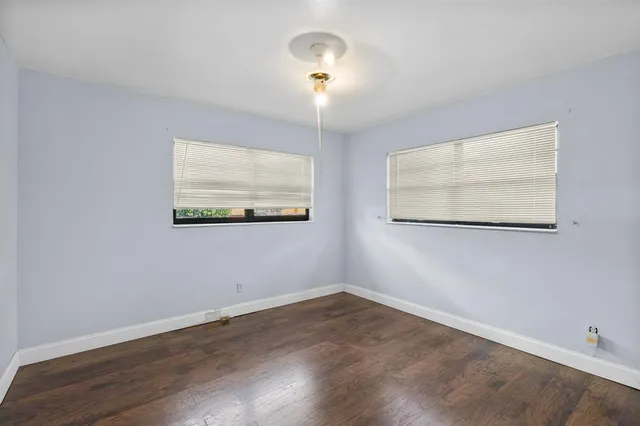 an empty room with wooden floor and window