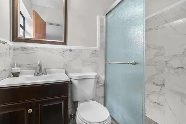 a bathroom with a toilet sink vanity and mirror
