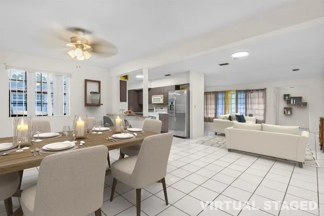 a dining hall with stainless steel appliances kitchen island granite countertop a dining table chairs and a refrigerator