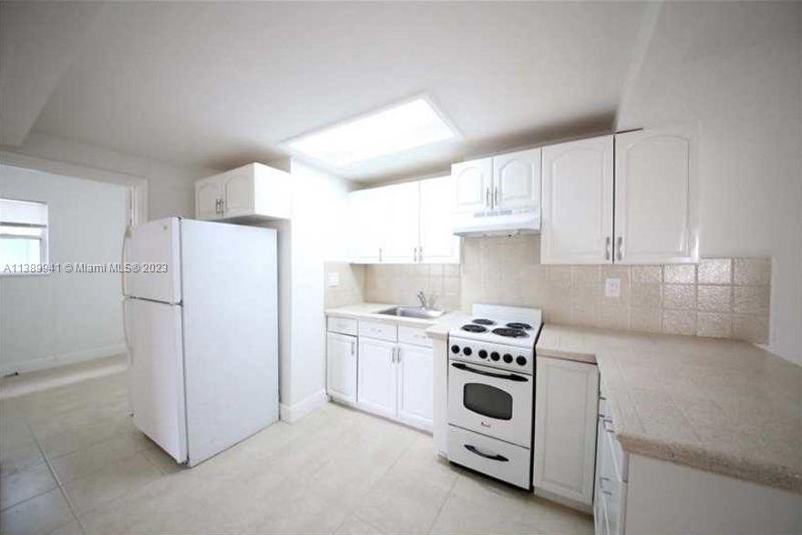 Normandy Isle Miami Beach, FL 33141 - Photo 4 of 13 a kitchen with white cabinets and white appliances