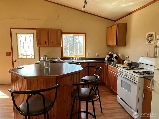 a kitchen with stainless steel appliances granite countertop a sink a stove a table and chairs