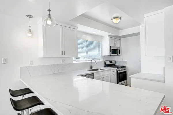 a kitchen with granite countertop a sink a stove and refrigerator