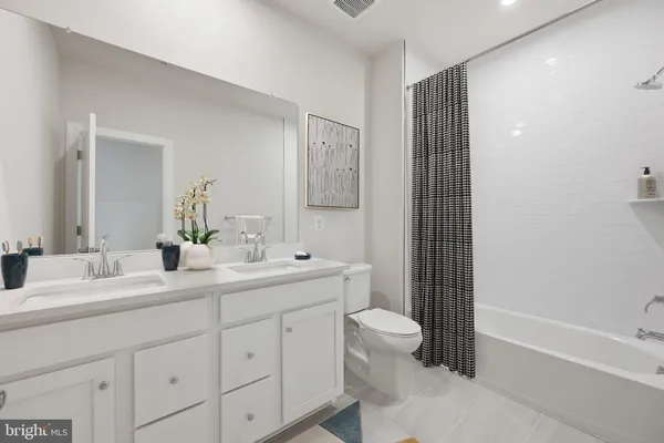 a bathroom with a double vanity sink toilet mirror and bathtub