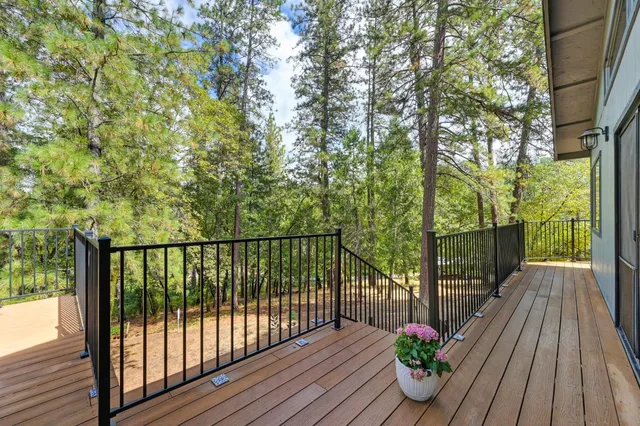 a view of a house with large tree and wooden fence