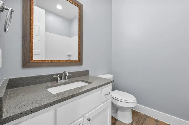 a bathroom with a granite countertop sink a toilet and a mirror