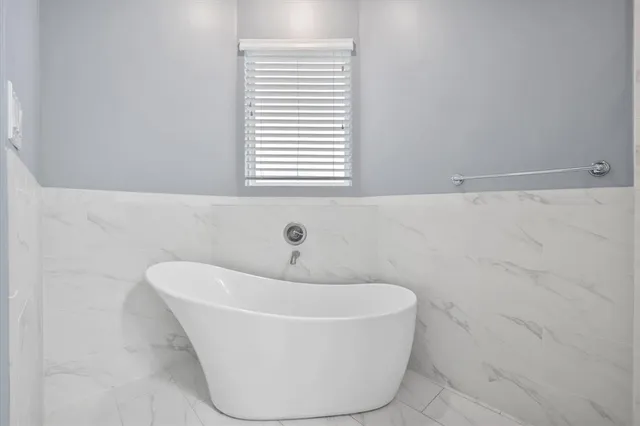 a white bath tub sitting in a bathroom next to a window