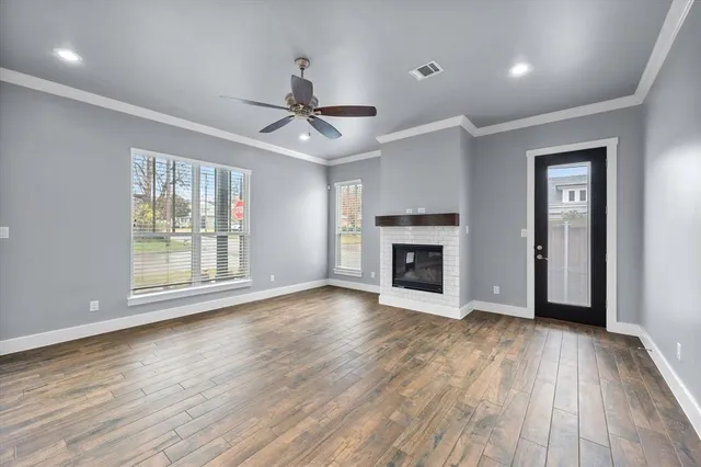 a view of an empty room with wooden floor fireplace and a window