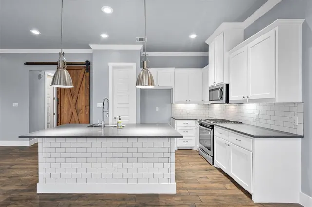 a kitchen with stainless steel appliances granite countertop wooden cabinets and a wooden floor