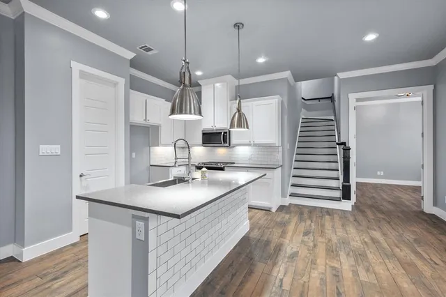 a kitchen with stainless steel appliances granite countertop a sink a stove and a wooden floors