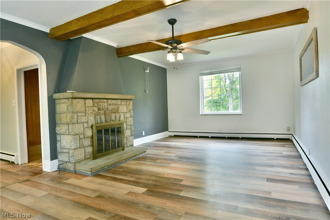 892 Yankee Run Road Masury, OH 44438 - Photo 26 of 50 Stone-clad fireplace with hearth, wood-finish flooring, exposed ceiling beams, and a ceiling fan with integrated lighting