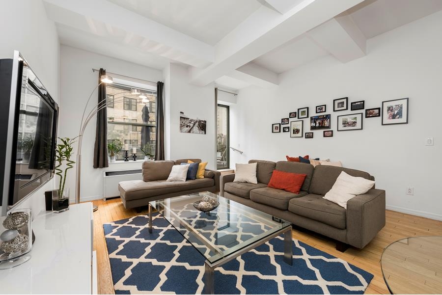 99 John Street, Unit 1408 Manhattan, NY 10038 - Photo 1 of 1 a living room with furniture a flat screen tv and a couch
