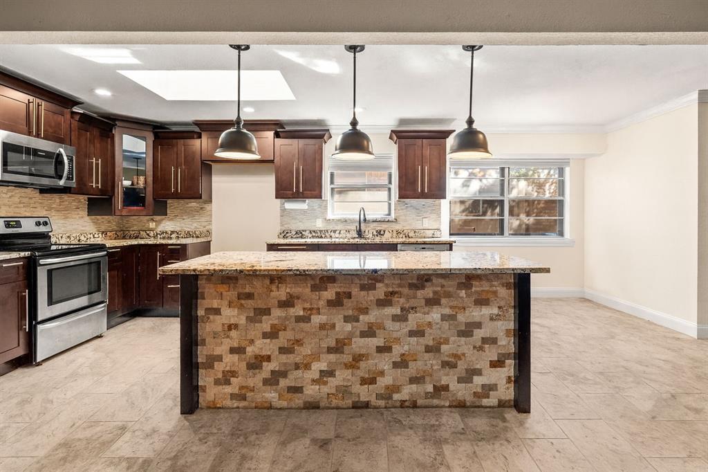 9552 Timberleaf Drive Dallas, TX 75243 - Photo 9 of 38 a kitchen with stainless steel appliances kitchen island granite countertop a stove a sink and a microwave