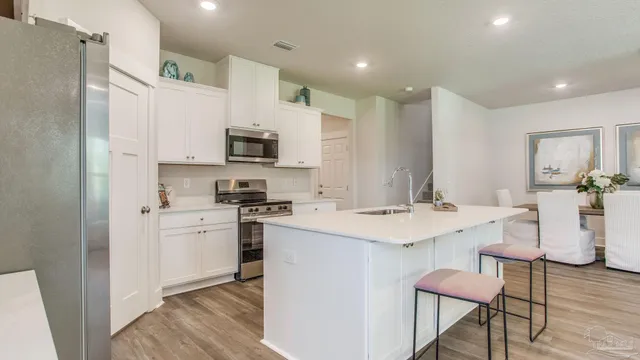 a kitchen with stainless steel appliances a sink cabinets and wooden floor