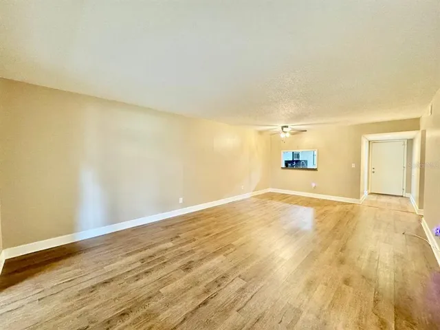 a view of empty room with wooden floor and fan