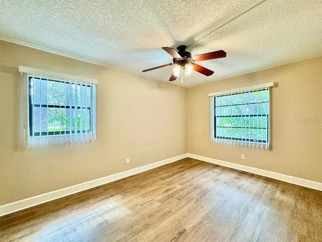 a view of empty room with wooden floor and fan