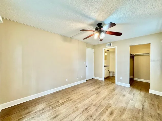 a view of a big room with wooden floor and a chandelier fan