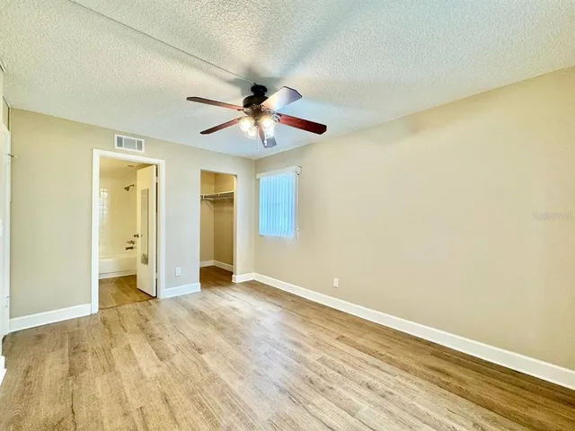 a view of a big room with wooden floor and a chandelier fan