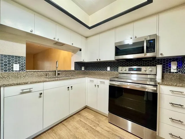 a kitchen with stainless steel appliances granite countertop a stove a microwave and a sink