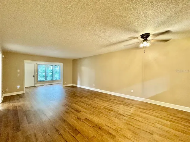 a view of empty room with wooden floor and fan