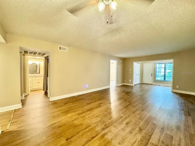 a view of an empty room with window and wooden floor