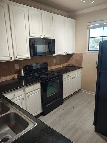 a kitchen with granite countertop a stove sink and cabinets