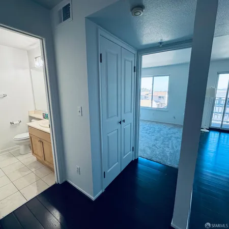 a view of a hallway with wooden floor and a bathroom
