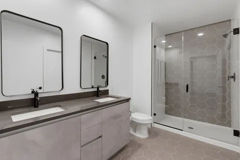 a bathroom with a double vanity sink toilet and shower