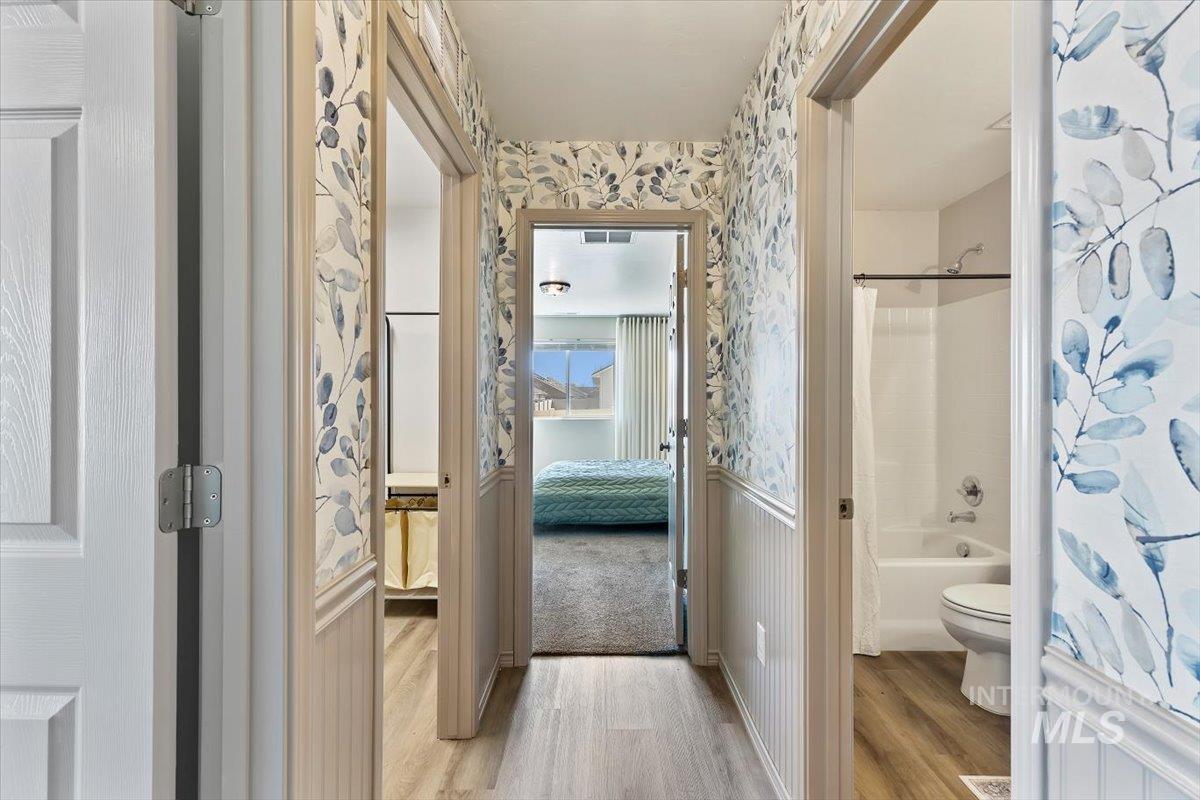 12781 Ashfield Street Caldwell, ID 83607 - Photo 17 of 36 Full bath featuring wallpapered walls, shower / bath combo with shower curtain, ensuite bathroom, and light wood-style flooring