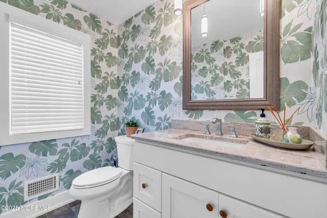 a bathroom with a granite countertop sink and a toilet