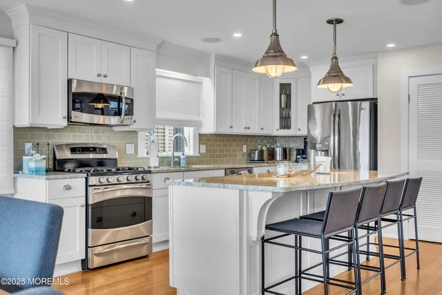 a kitchen with stainless steel appliances granite countertop a stove a sink and a refrigerator