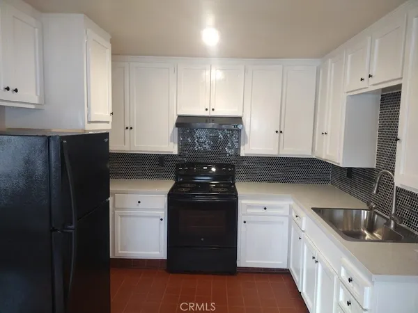 a kitchen with granite countertop white cabinets and refrigerator