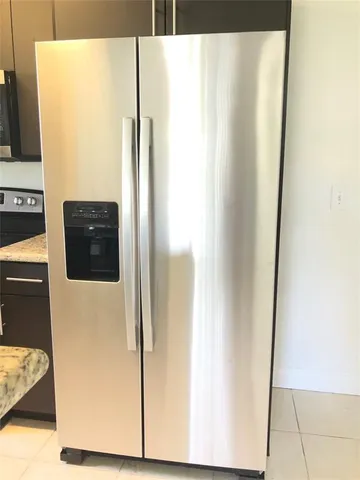 a view of a refrigerator in kitchen and an empty room