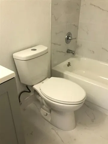 a white toilet sitting next to a bath tub
