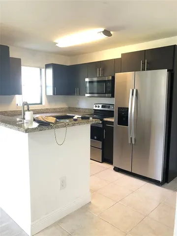 a kitchen with stainless steel appliances granite countertop a refrigerator a stove a sink a microwave and island