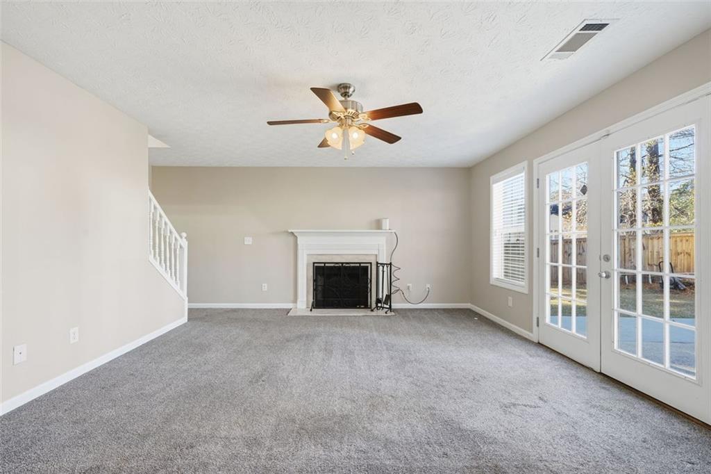 921 Roxeywood Drive Winder, GA 30680 - Photo 19 of 56 an empty room with windows fireplace and a ceiling fan
