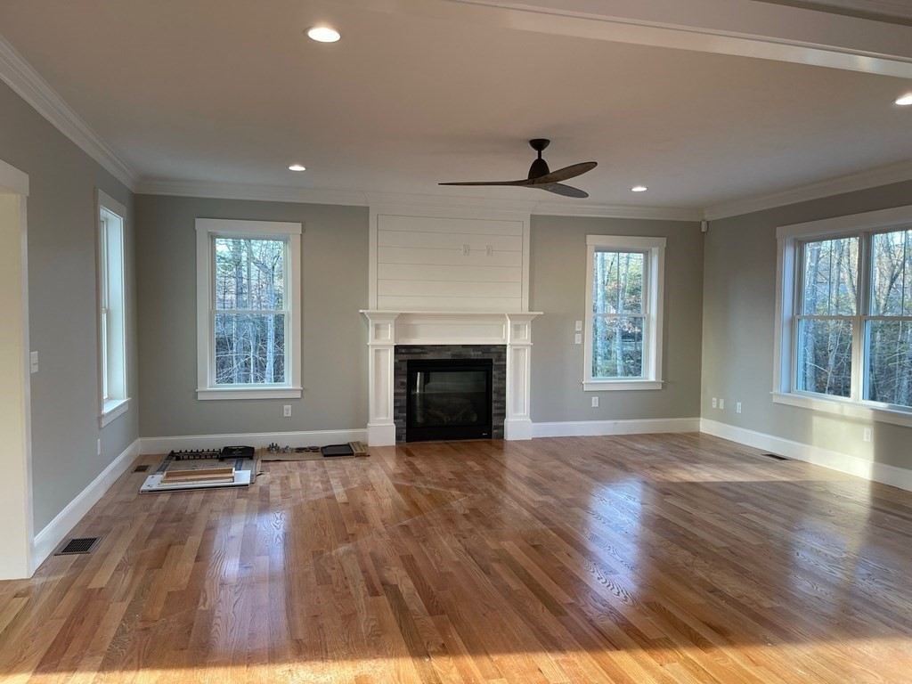 27 Paugus Trail Groton, MA 01450 - Photo 13 of 29 an empty room with wooden floor fireplace and windows