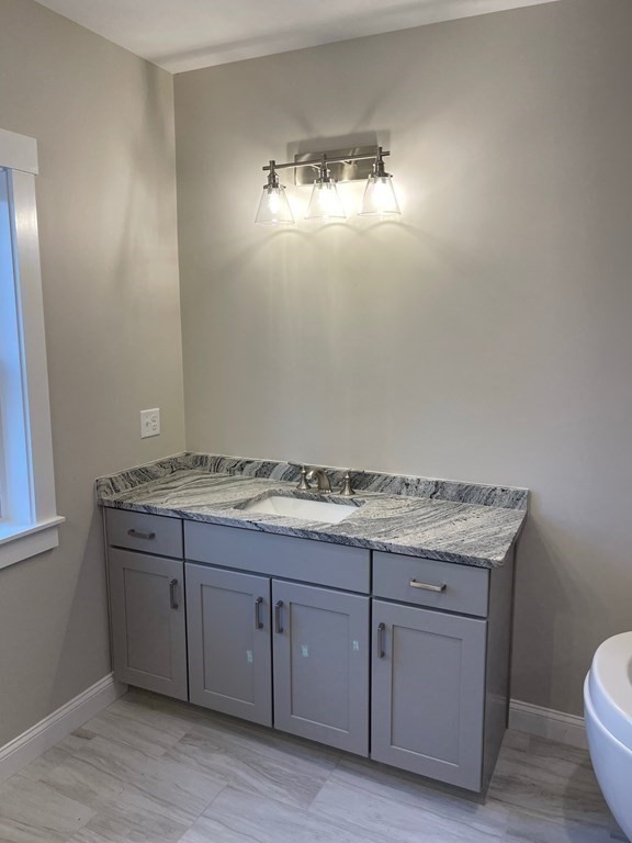 27 Paugus Trail Groton, MA 01450 - Photo 25 of 29 a bathroom with a granite countertop toilet a sink and chandelier