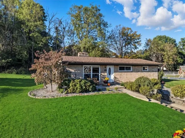 a front view of a house with a garden and trees