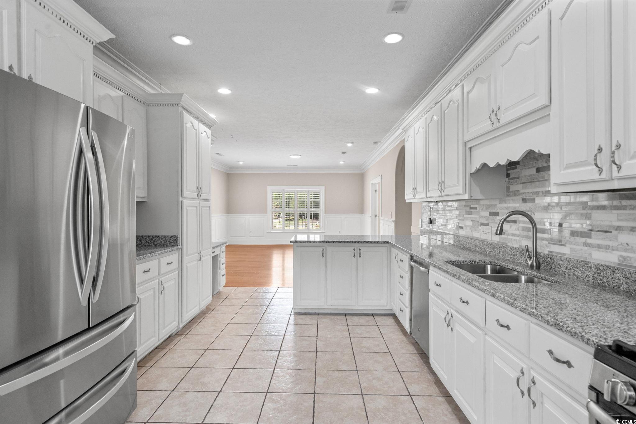 6912 Bay Road Myrtle Beach, SC 29588 - Photo 11 of 38 Kitchen featuring a wainscoted wall, stainless steel appliances, white cabinets, a peninsula, and a decorative wall