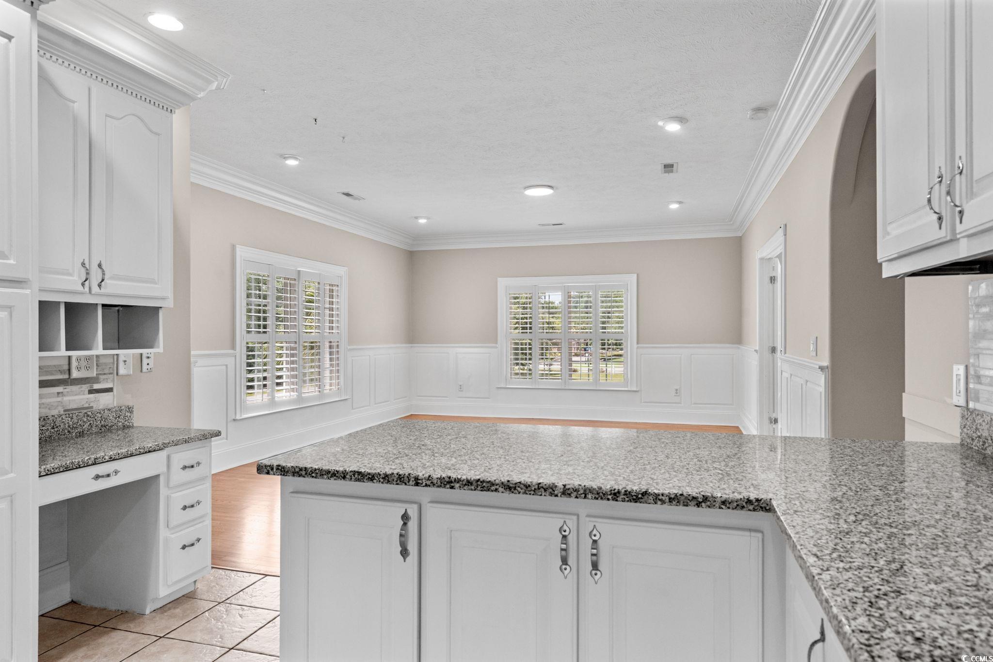 6912 Bay Road Myrtle Beach, SC 29588 - Photo 15 of 38 Kitchen featuring plenty of natural light, ornamental molding, white cabinets, a textured ceiling, and light stone countertops