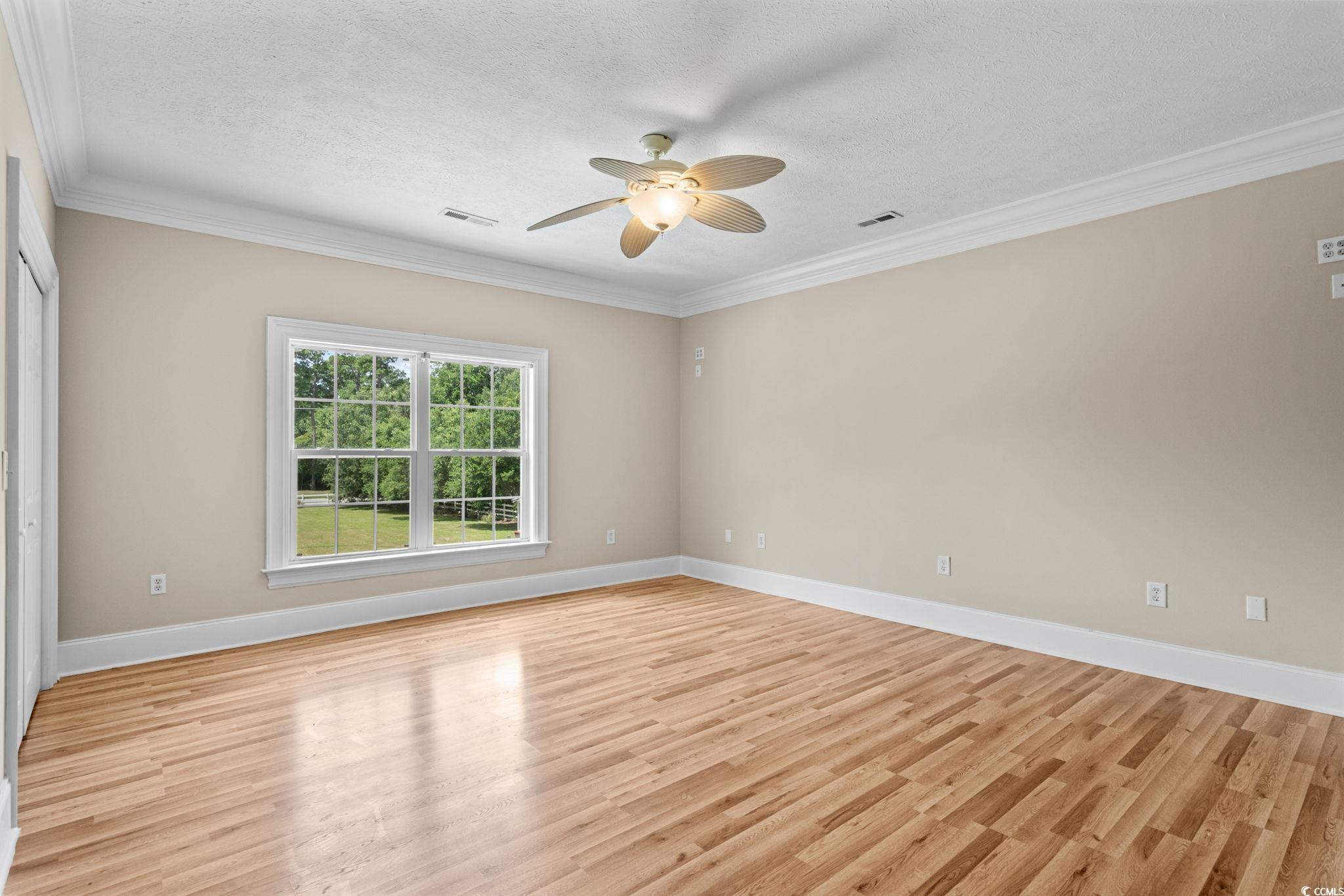 6912 Bay Road Myrtle Beach, SC 29588 - Photo 17 of 38 Empty room with ornamental molding, light wood-style floors, a textured ceiling, and a ceiling fan