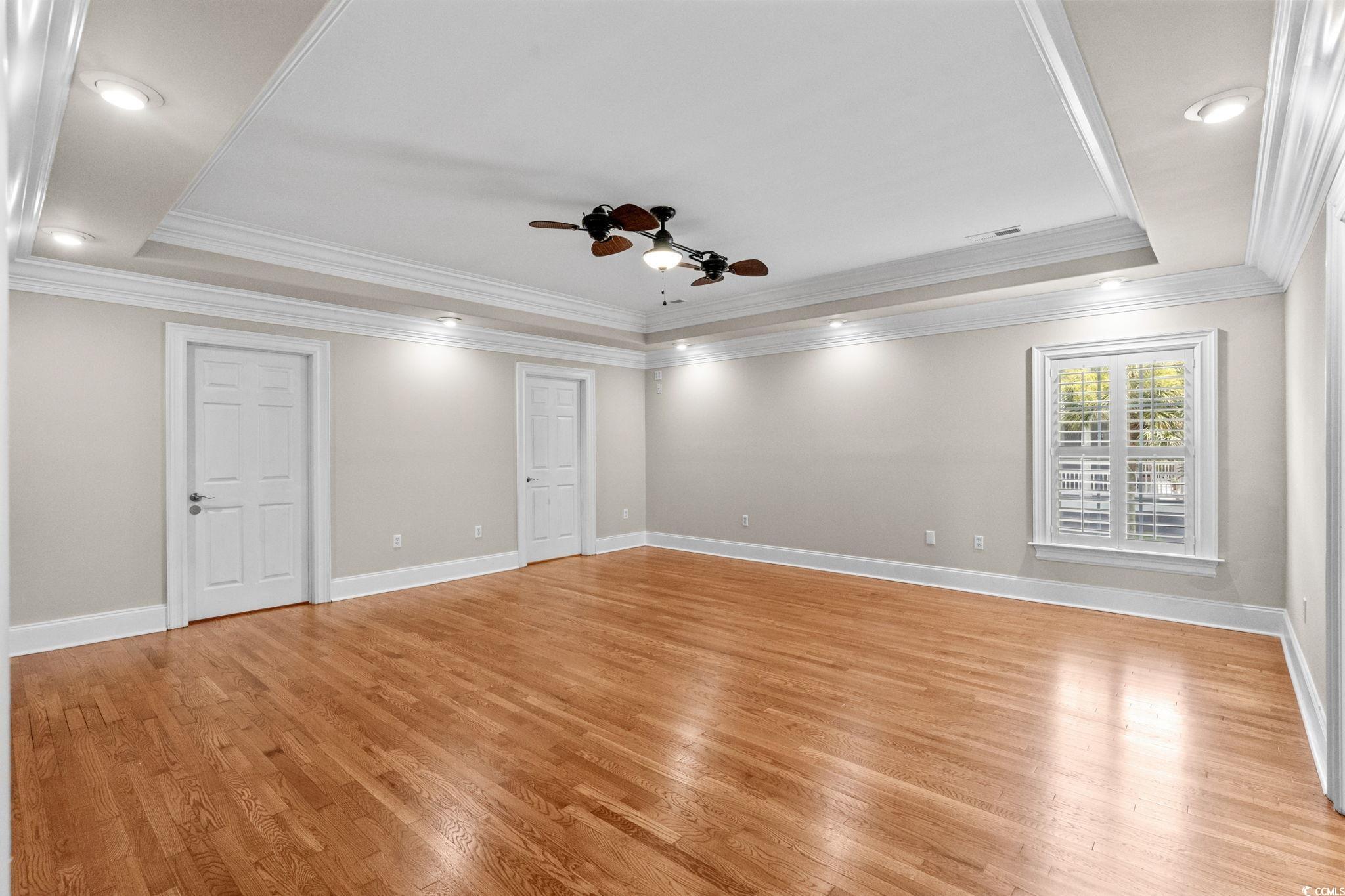 6912 Bay Road Myrtle Beach, SC 29588 - Photo 19 of 38 Primary Bedroom with a raised ceiling, crown molding, light wood finished floors, ceiling fan, and recessed lighting