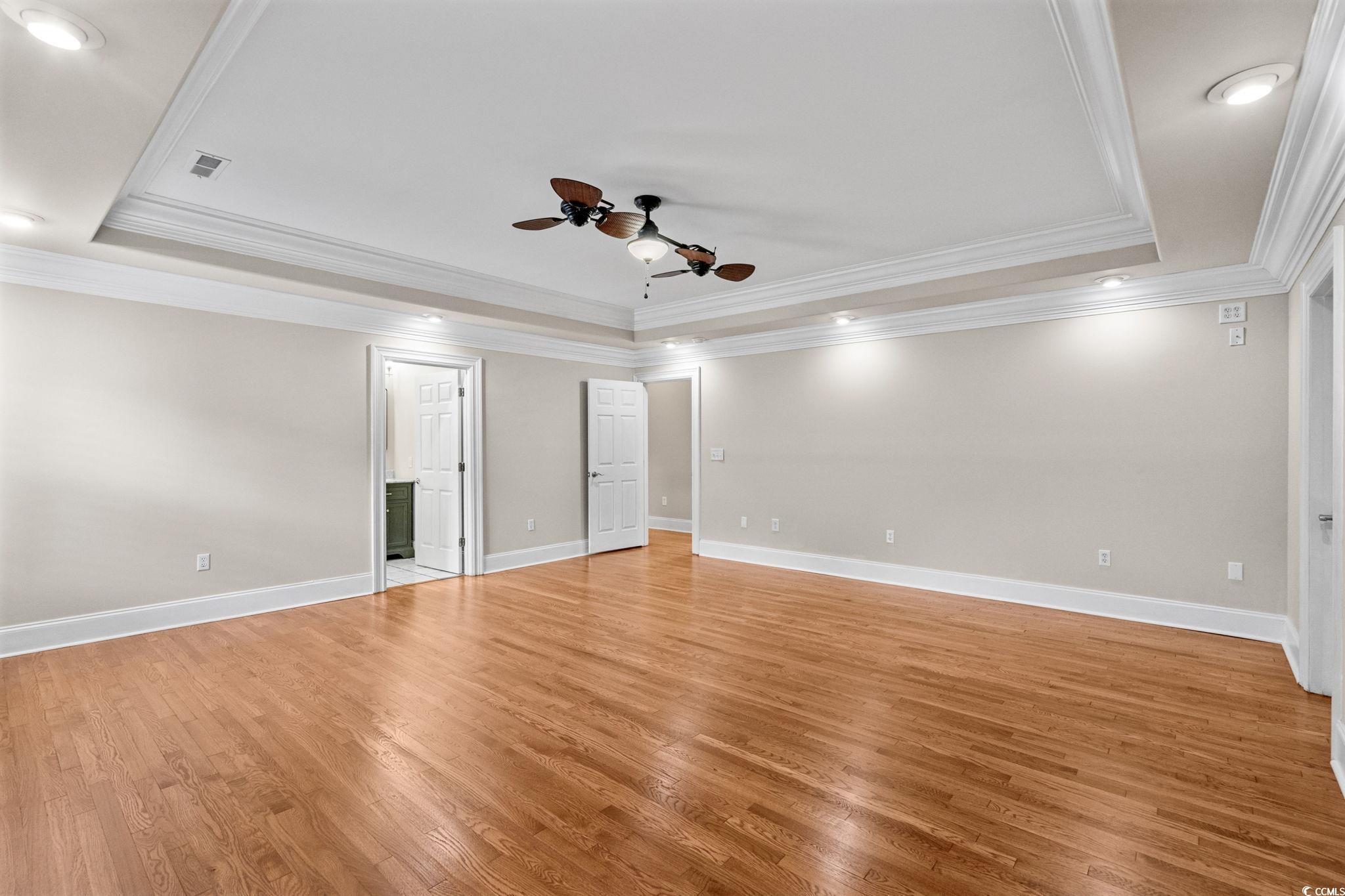 6912 Bay Road Myrtle Beach, SC 29588 - Photo 21 of 38 Primary bedroom with a raised ceiling, unusual ceiling fan, ornamental molding, light wood-style floors, recessed lighting and private bath