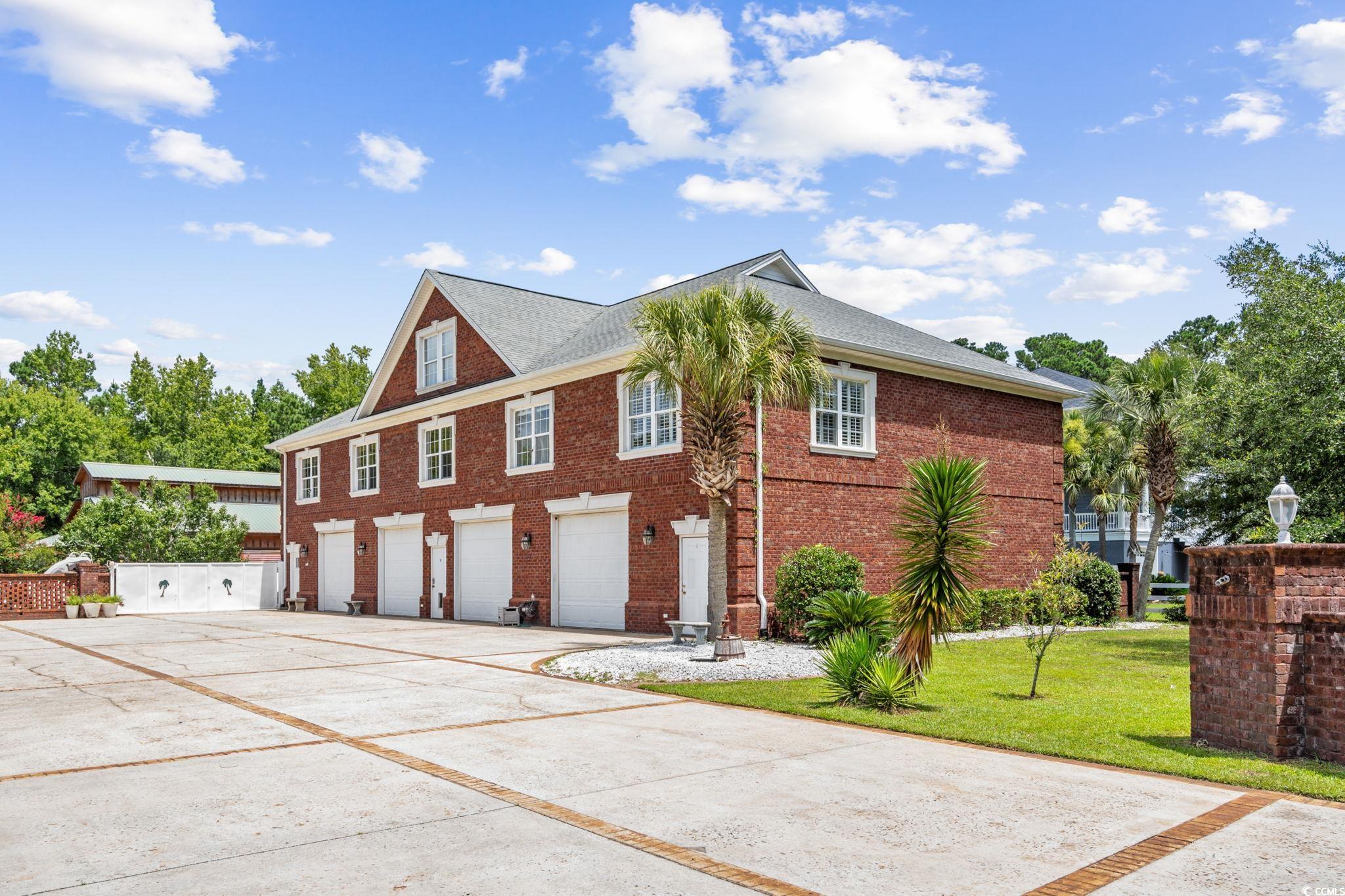 6912 Bay Road Myrtle Beach, SC 29588 - Photo 24 of 38 View of side of property featuring concrete driveway, brick siding, an attached garage, and a yard