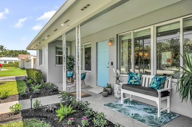 a patio with table and chairs potted plants and floor to ceiling window