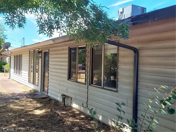 an empty room with wooden floor chandelier and windows