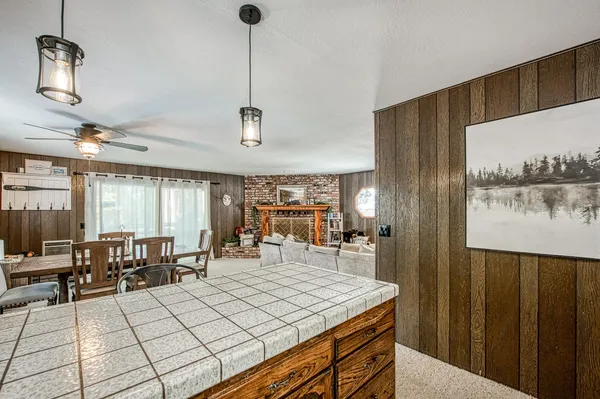 a dining hall with stainless steel appliances kitchen island granite countertop a table chairs in it and a large window